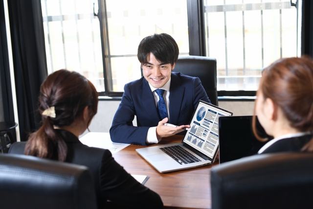 ノートパソコンで説明する若いビジネスマン