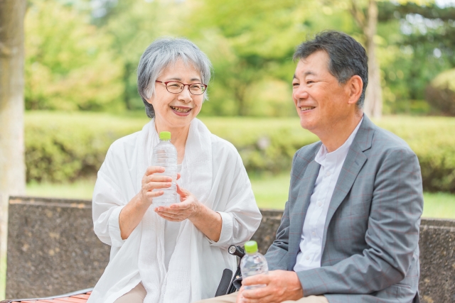 散歩中に水を飲んで休憩するシニア夫婦